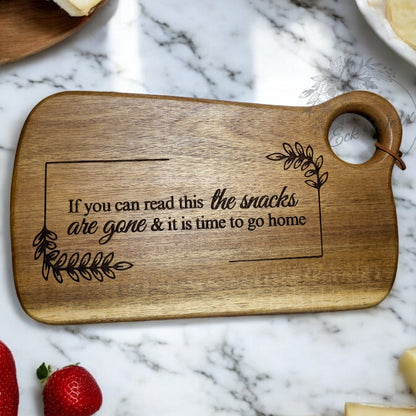 A wooden charcuterie board with a humorous French phrase engraved on it.